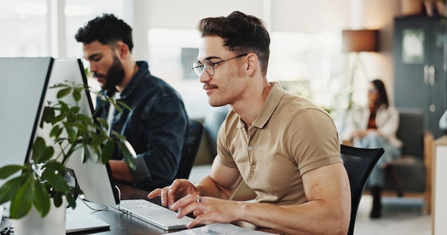 Computer typing and web development with man programmer in creative workplace for coding or design Cybersecurity happy and system infrastructure with employee person in office as website developer