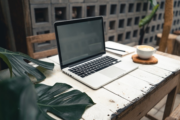 Computer und Hände arbeiten mit dem Kaffee am Tisch