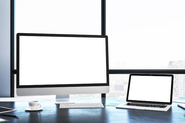 Computer und Laptop mit leerem Bildschirm im modernen Büroinnenraum