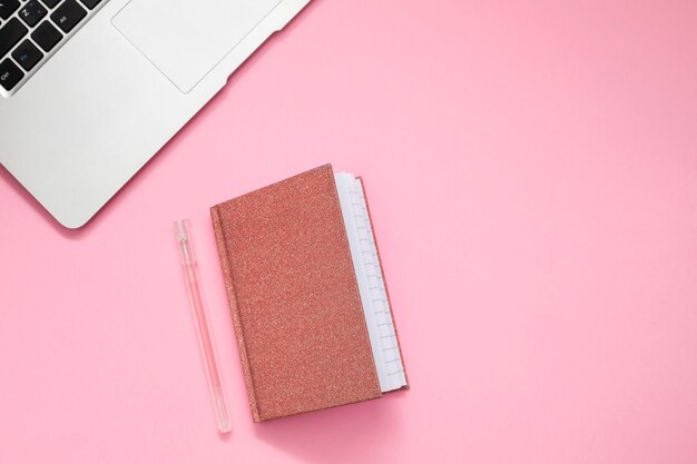 Computer und Taschenbuch auf rosa Hintergrund