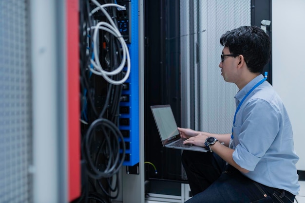 Computeringenieur richtet ein Netzwerk im Serverraum einSystems-WartungstechnikerMännlicher Ingenieur arbeitet im Serverraum eines modernen Rechenzentrums