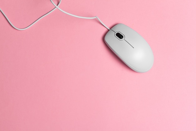 Computermaus mit einer Schnur über einem rosa Papier