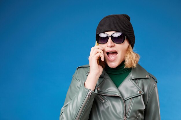 Comunicação móvel Vista de retrato da cintura para cima de uma jovem adulta bonita, ligando para o parceiro falando no celular com uma expressão agitada Foto de estúdio interior isolada em fundo azul