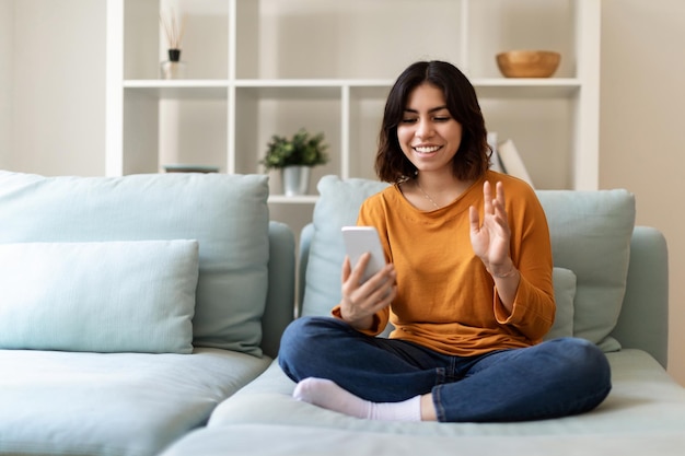 Comunicação online mulher árabe feliz fazendo chamada de vídeo via smartphone em casa