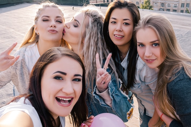 Comunicação social moderna. Amizade feminina. Garotas felizes tirando selfie do ponto de vista da rua