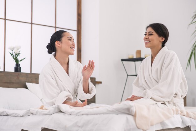 Comunicación agradable. Amigos encantados positivos hablando entre sí mientras están en el salón de spa