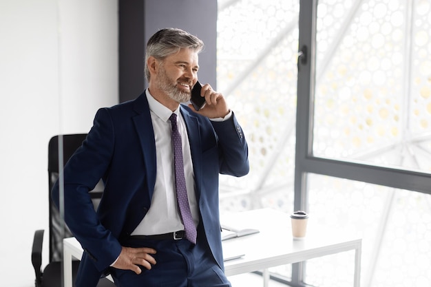 Comunicación corporativa hombre de negocios de mediana edad con traje con llamada móvil en la oficina