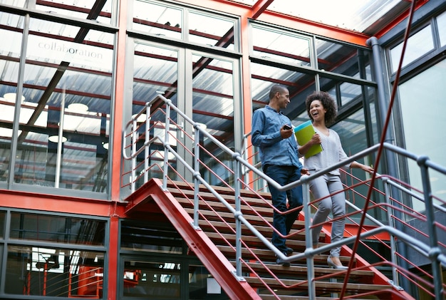 La comunicación es la clave del éxito Dos colegas bajan las escaleras uno al lado del otro en su edificio