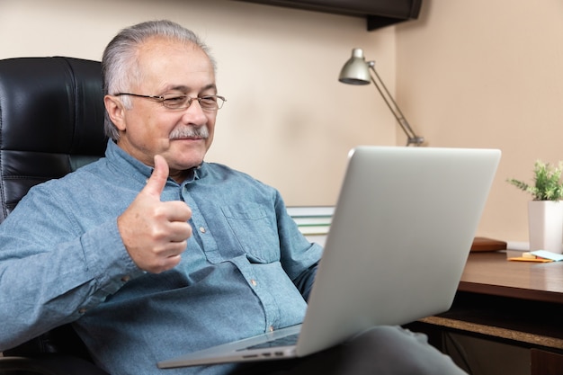 Comunicación en línea del hombre mayor. El anciano hace videollamadas hablando con familiares o amigos mediante la aplicación de videoconferencia