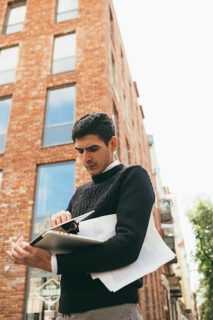 Comunicación de movilidad gracias a la tecnología moderna. conexión en línea. hombre de negocios trabajando estilo de vida al aire libre con documentos usando laptop. fondo urbano