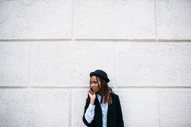 Comunicaciones sociales. Mujer negra con estilo. Chica afroamericana sobre fondo blanco con espacio libre. Juventud moderna, modelo, concepto de belleza.