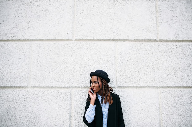 Comunicações sociais. Mulher negra elegante. Garota afro-americana em fundo branco com espaço livre. Juventude moderna, modelo de moda, conceito de beleza