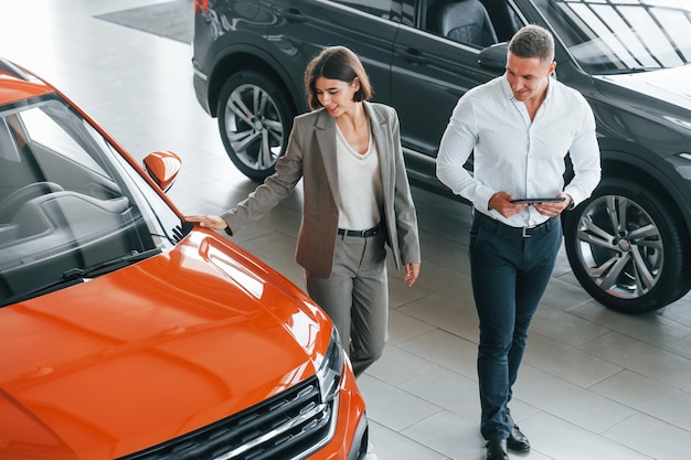 Comunicarse entre sí Hombre en ropa formal ayudando al cliente con la elección del automóvil