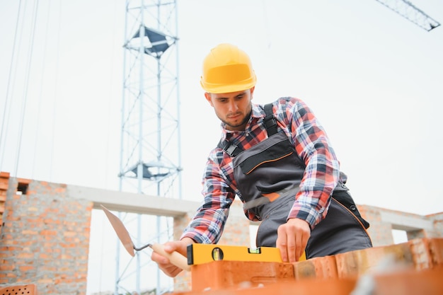 Comunicarse con el tipo de la grúa Trabajador de la construcción en uniforme y equipo de seguridad tiene trabajo en la construcción