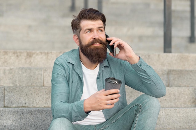 Comunicémonos a través de una llamada Hipster beba café hablando por teléfono inteligente al aire libre Conversación telefónica y comunicación Comunicación móvil Comunicación empresarial Uso de tecnología de comunicación