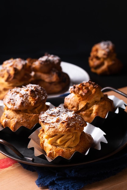 Conceito alimentar Homemade Caramel Choux a la cream ou Choux cream puffs em fundo escuro com espaço de cópia