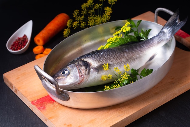 Foto conceito alimentar peixe robalo branco em bandeja tustic em placa de madeira em fundo preto com espaço de cópia
