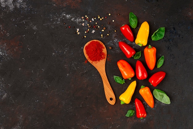 Conceito alimentar pequeno pimentão colorido em uma mesa escura com uma colher de pimenta e ervilhas