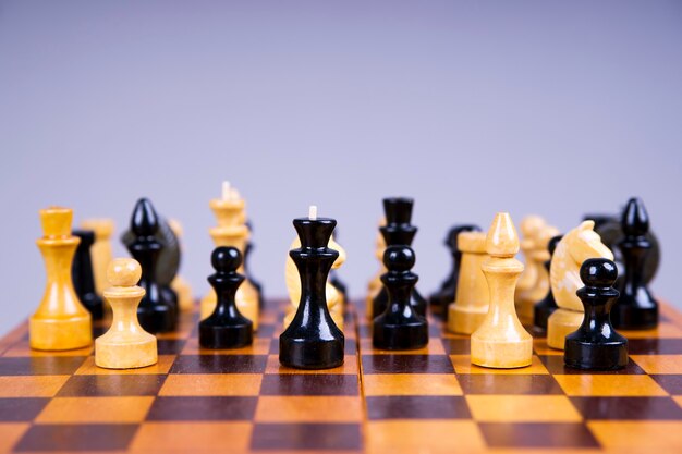 Conceito com peças de xadrez em um tabuleiro de xadrez de madeira em um fundo cinza