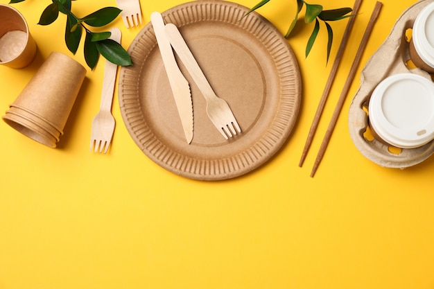 Conceito com utensílios de mesa ecológicos e planta em amarelo, copie o espaço