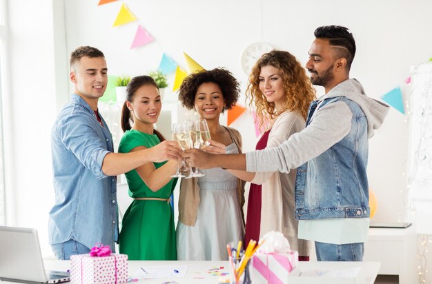 Foto conceito corporativo, de celebração e de feriados - equipe feliz tocando copos de vinho espumante não alcoólico na festa de aniversário do escritório