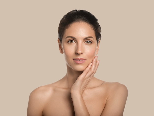 Conceito cosmético de rosto de beleza de pele saudável de mulher bonita tocando seu fundo de cor de rosto. Marrom.