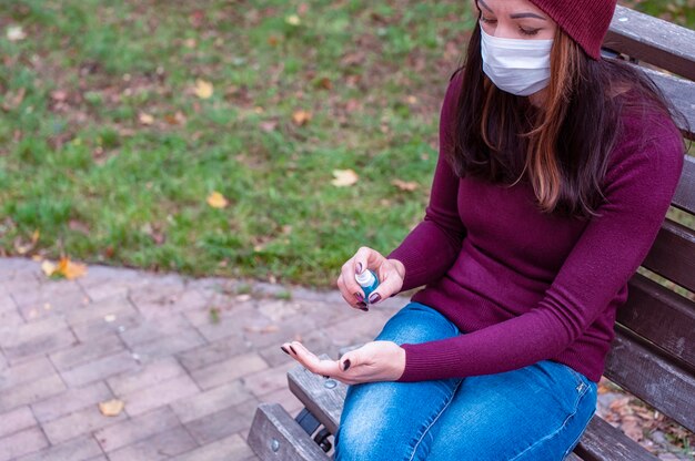 Conceito COVID-19. Mulher com máscara médica, lavando as mãos com álcool gel desinfetante. Proteção e prevenção contra coronavírus.