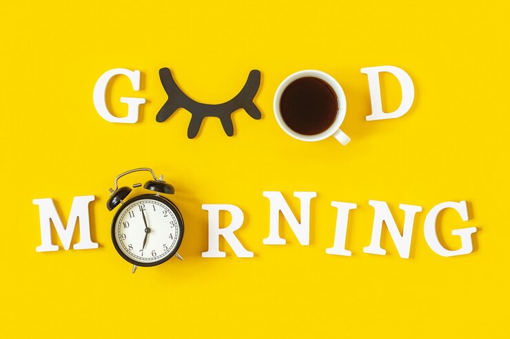 Foto conceito criativo de bom dia letras brancas cílios pretos despertador e xícara de café em fundo amarelo vista superior cartão de saudação plano lay