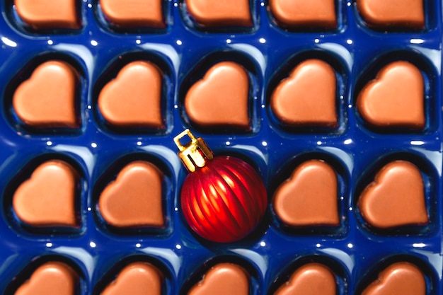 Conceito criativo de Natal com bola de Natal em caixa de chocolates em forma de coração. Vista do topo.