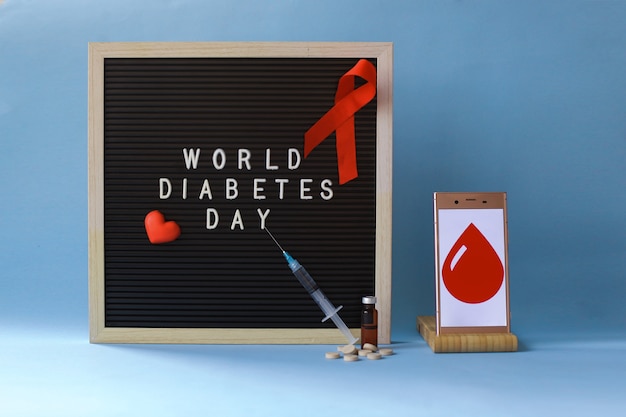 Conceito criativo plano leigo do Dia Mundial da Diabetes com fita vermelha, drogas e seringa de símbolo de sangue