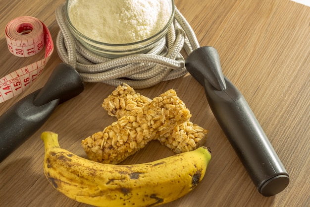 Conceito da aptidão com a proteína e as bananas do soro da fita da corda de salto dos pesos.