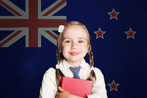 Conceito da Nova Zelândia com uma menina estudante com um livro contra o fundo da bandeira da Nova Zelandia