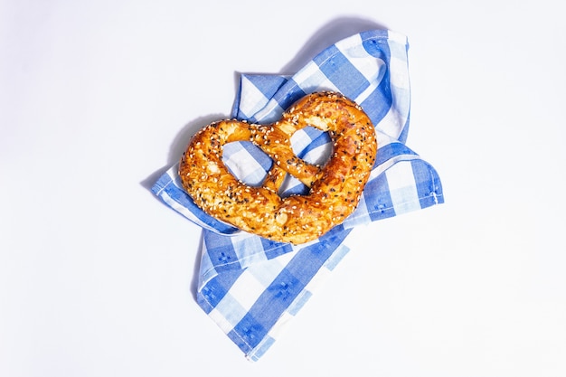 Conceito da oktoberfest - pretzel em um guardanapo tradicional, isolado no fundo branco. uma luz forte, sombra escura da moda