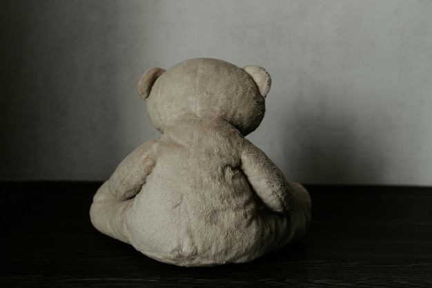 Conceito de abuso infantil Urso de pelúcia sentado sozinho em uma sala