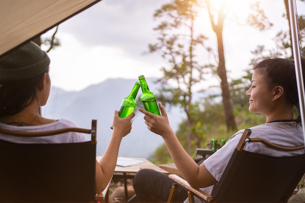 Conceito de acampamento cheers garrafa de vidro acampando pessoas juntas em seu acampamento na montanha