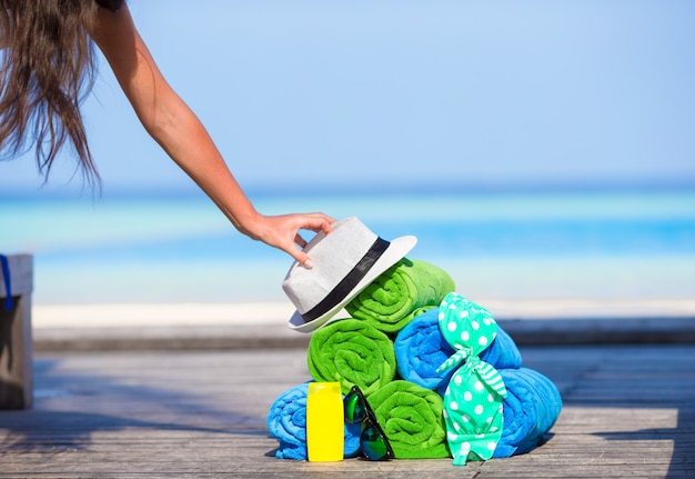 Conceito de acessórios de férias de praia e verão - close-up de toalhas coloridas, chapéu, bolsa e protetor solar