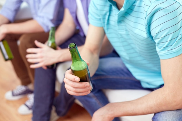 conceito de álcool e pessoas - homens com garrafas de cerveja sentados no sofá em casa