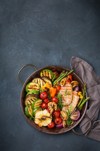 Conceito de alimentação vegan, vegetariano, sazonal, de verão. legumes grelhados em uma panela sobre uma mesa preta escura. vista superior do plano de fundo do espaço da cópia