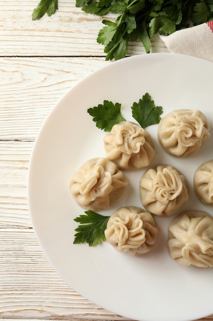 Conceito de almoço saboroso com prato de khinkali na mesa de madeira branca