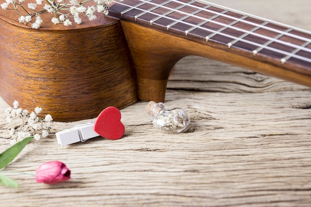 Foto conceito de amante de música do ukulele e cabide de coração vermelho na madeira velha