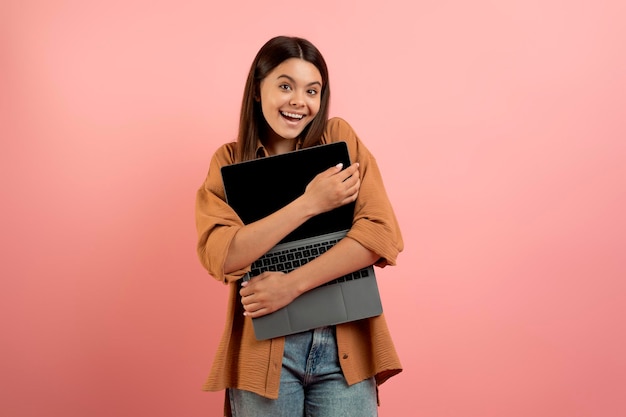 Foto conceito de amante de tecnologia adolescente alegre abraçando laptop com tela em branco