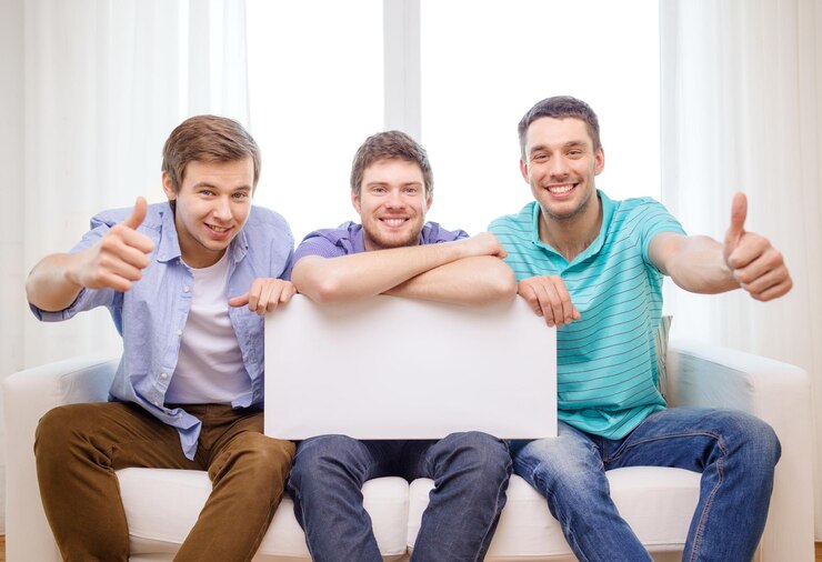 Foto conceito de amizade e publicidade - amigos do sexo masculino sorridentes segurando um quadro branco em branco e mostrando os polegares para cima