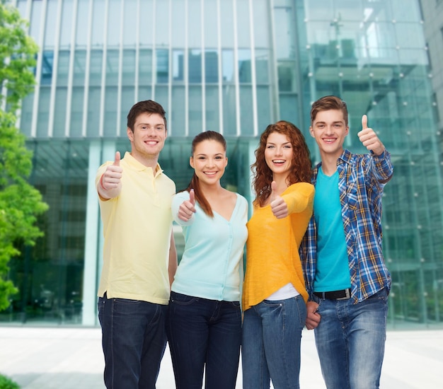 conceito de amizade, negócios, educação e pessoas - grupo de adolescentes sorridentes mostrando os polegares sobre o fundo do campus