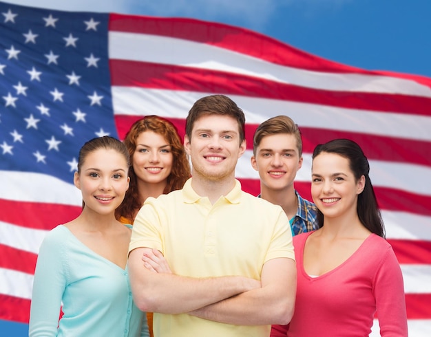 conceito de amizade, patriotismo e pessoas - grupo de adolescentes sorridentes em pé sobre o fundo da bandeira americana