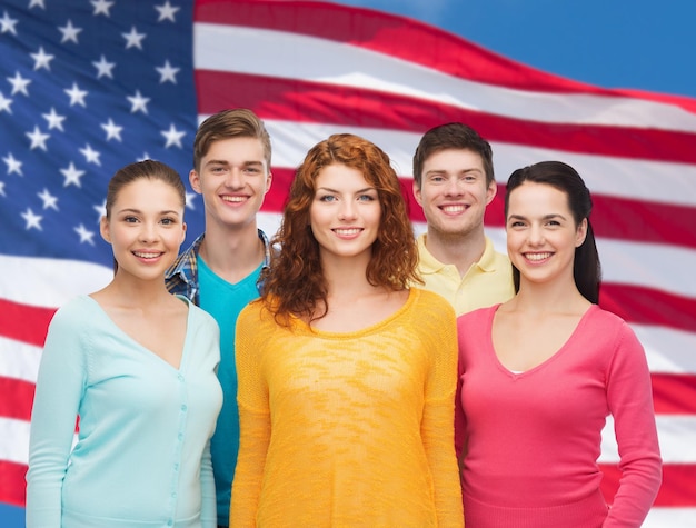 conceito de amizade, patriotismo e pessoas - grupo de adolescentes sorridentes em pé sobre o fundo da bandeira americana