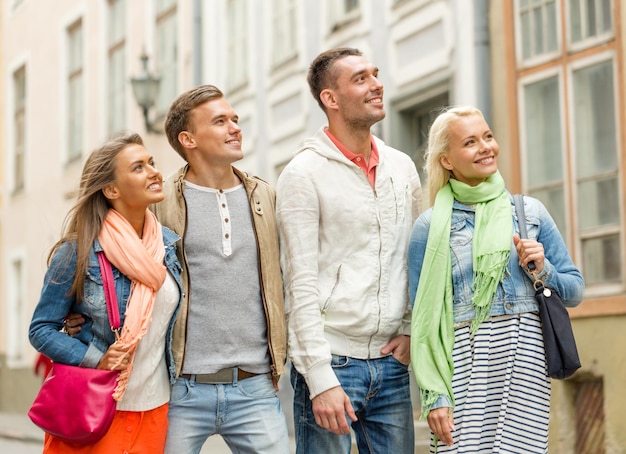 conceito de amizade, viagens e férias - grupo de amigos sorridentes andando na cidade