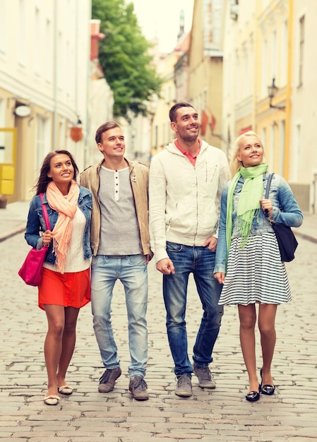 conceito de amizade, viagens e férias - grupo de amigos sorridentes andando na cidade