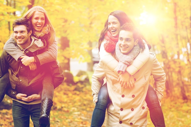 conceito de amor, amizade, família e pessoas - amigos sorridentes se divertindo no parque outono