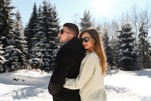 Conceito de amor e férias casal feliz abraçando e rindo ao ar livre no inverno na natureza