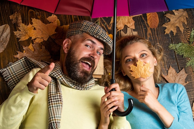 Conceito de amor e pessoas casal feliz sob guarda-chuva colorido família relaxa entre as folhas de outono feliz por estar por perto bom humor em qualquer clima permanecendo positivo e otimista